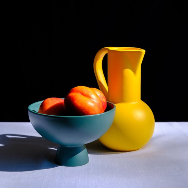 still life lighting nectarines in a bowl with a pitcher